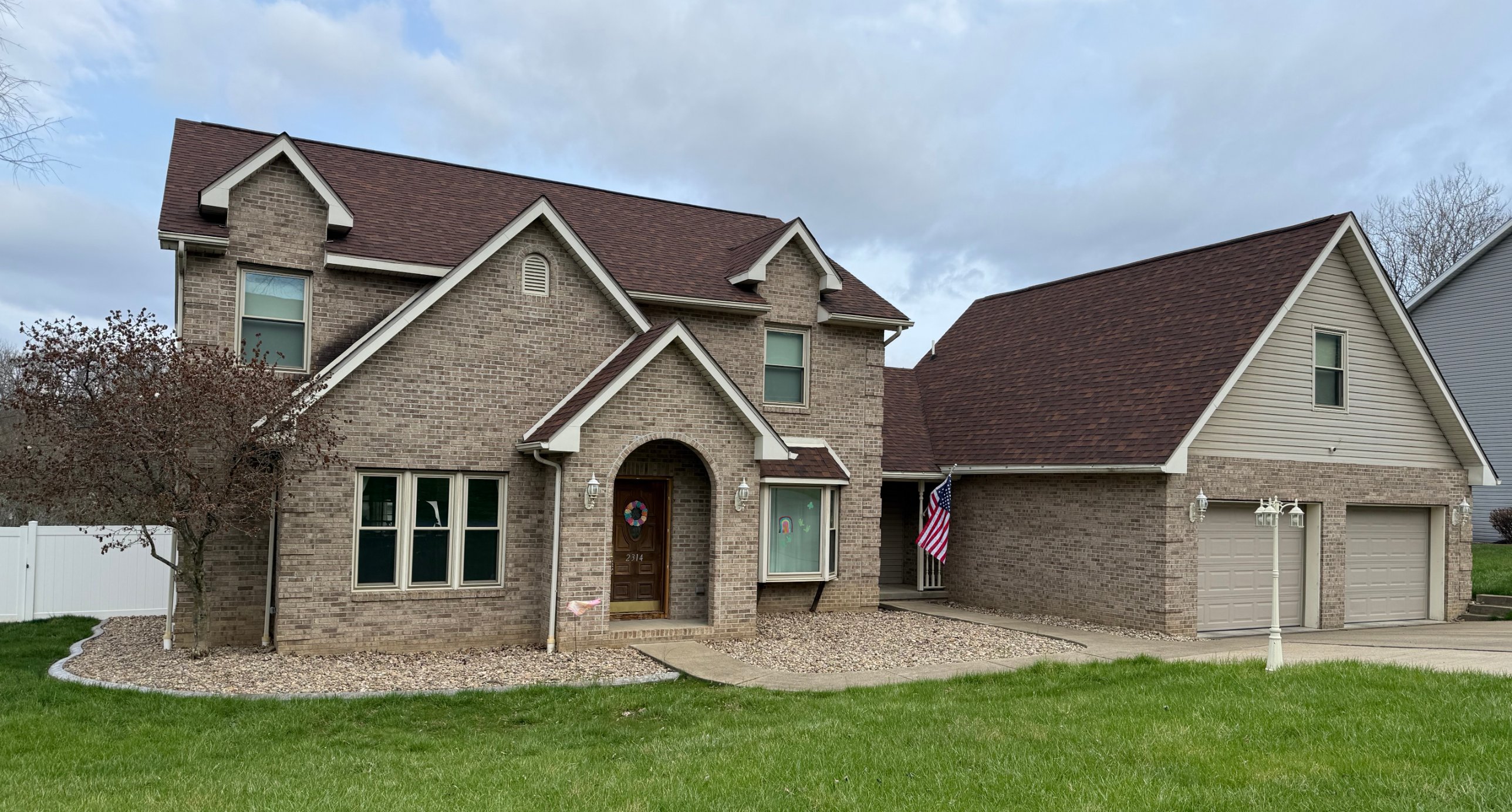 Front of 2314 Magnolia Drive: two-story brick home with arched entry and attached two-car garage